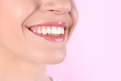 Young woman with healthy teeth and beautiful smile on color background, closeup. Space for text