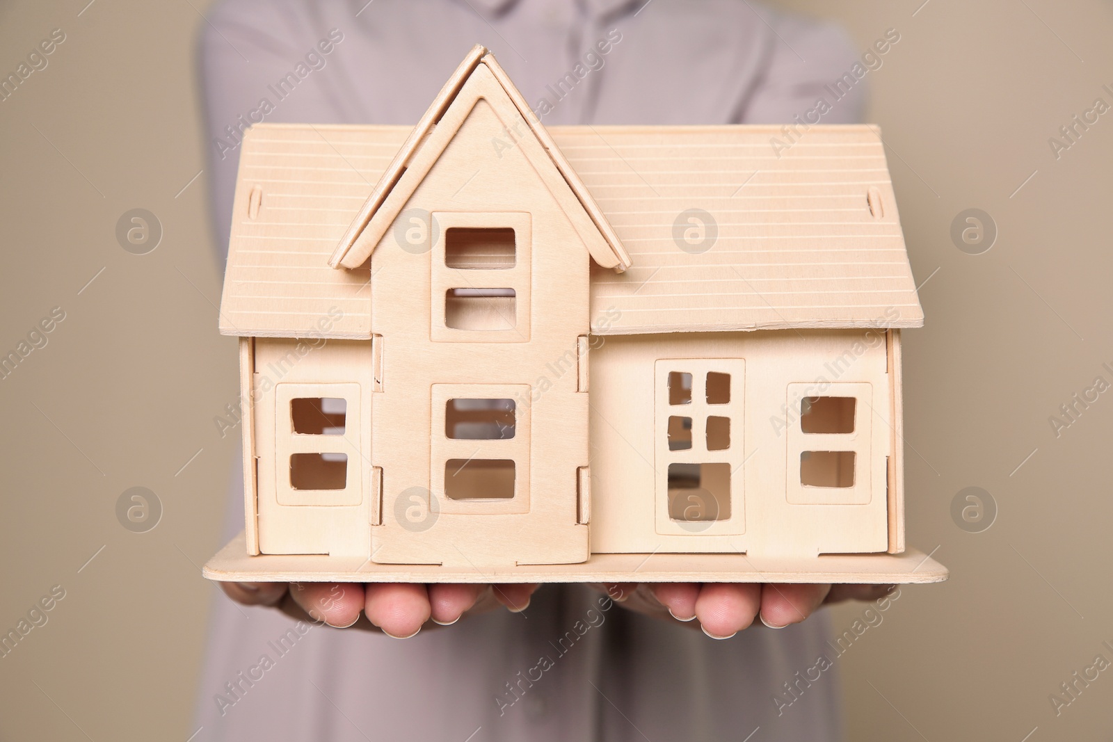 Photo of Young woman holding house model on color background, closeup