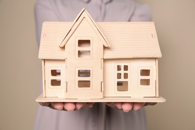 Photo of Young woman holding house model on color background, closeup
