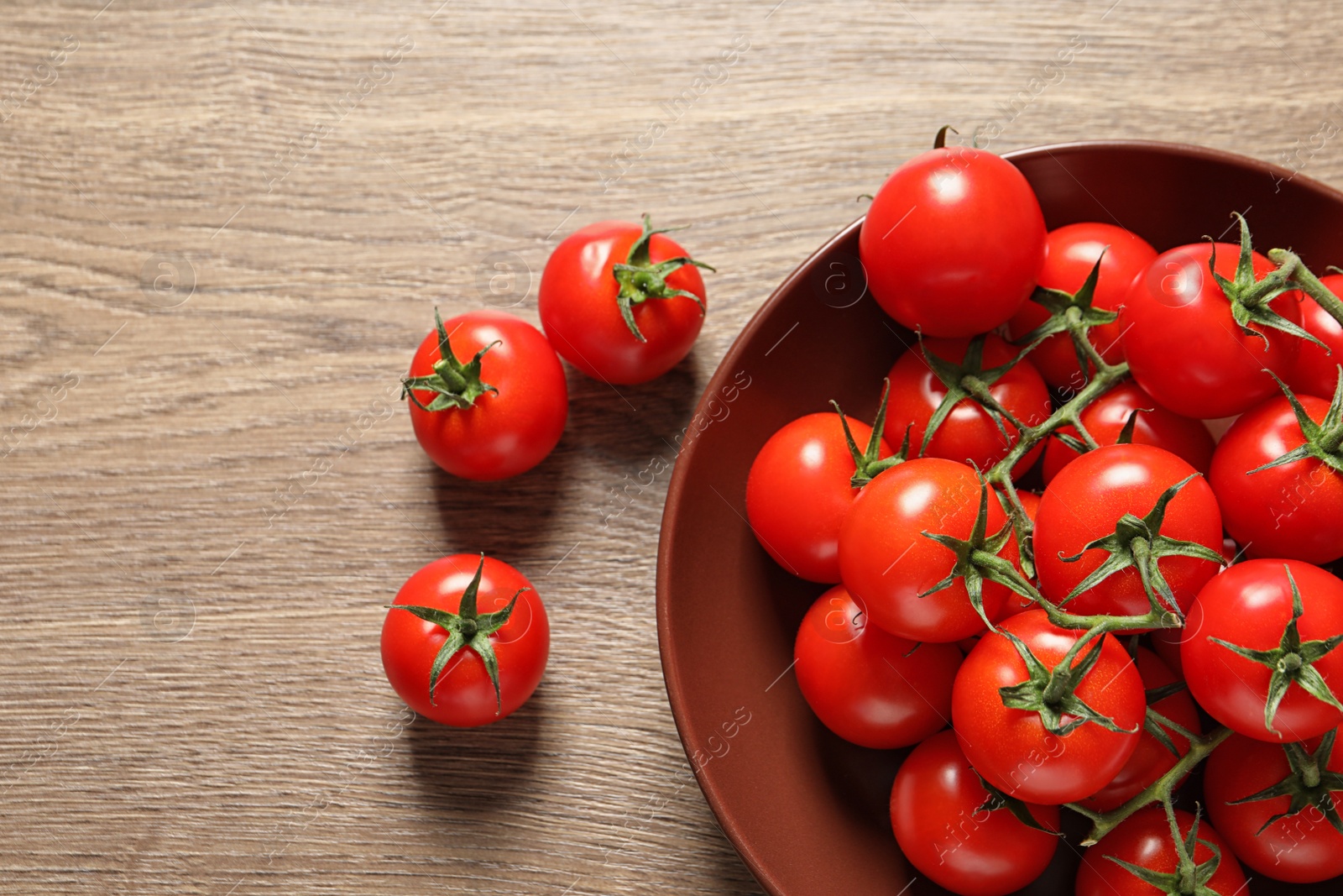 Photo of Plate with fresh cherry tomatoes on wooden background, top view