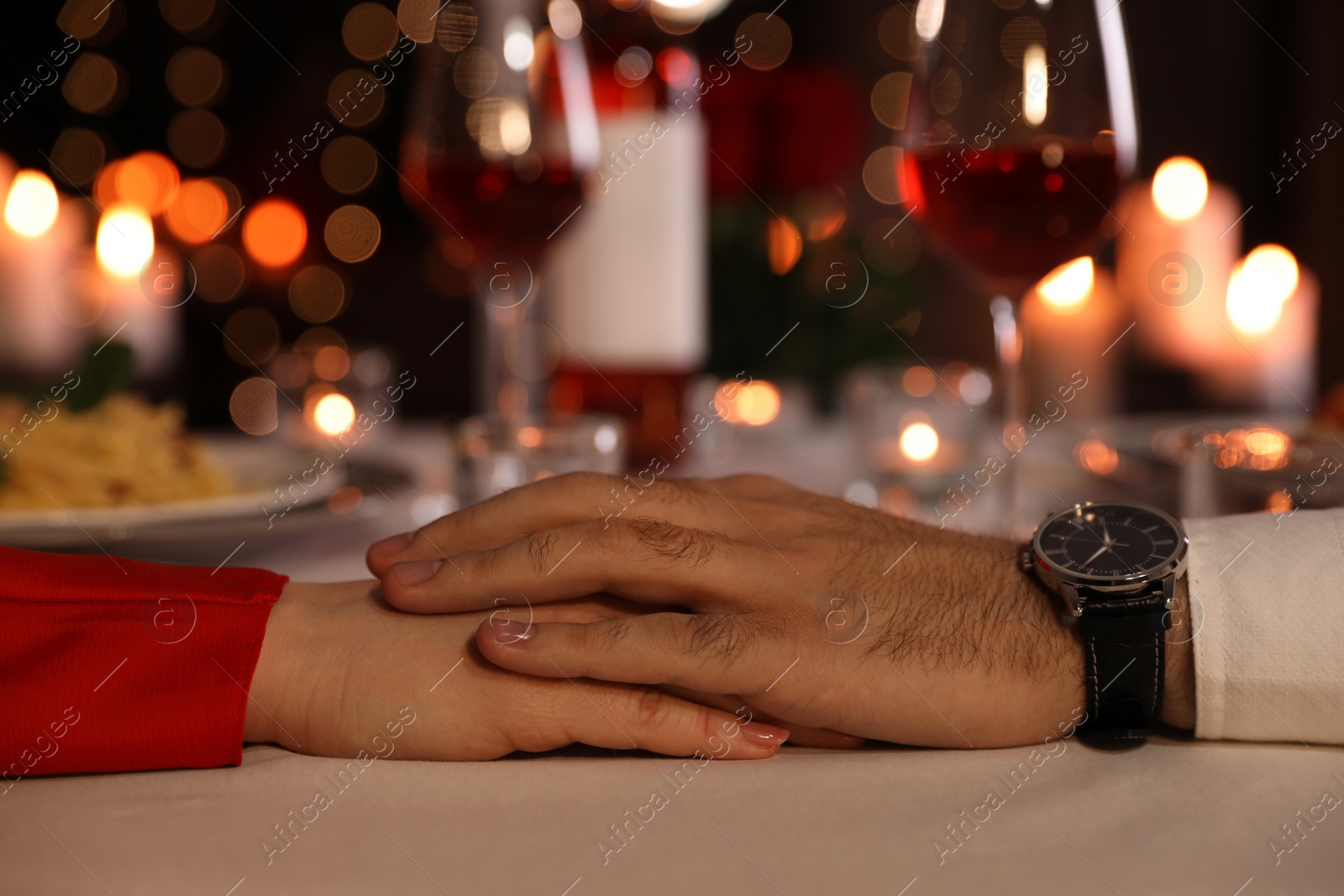 Photo of Couple holding hands together at table during romantic dinner in restaurant, closeup
