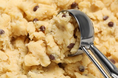 Scoop and raw dough for chocolate chip cookies as background, closeup