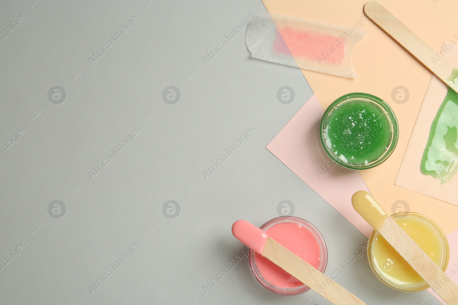 Photo of Flat lay composition with different types of wax and spatulas on color background. Space for text