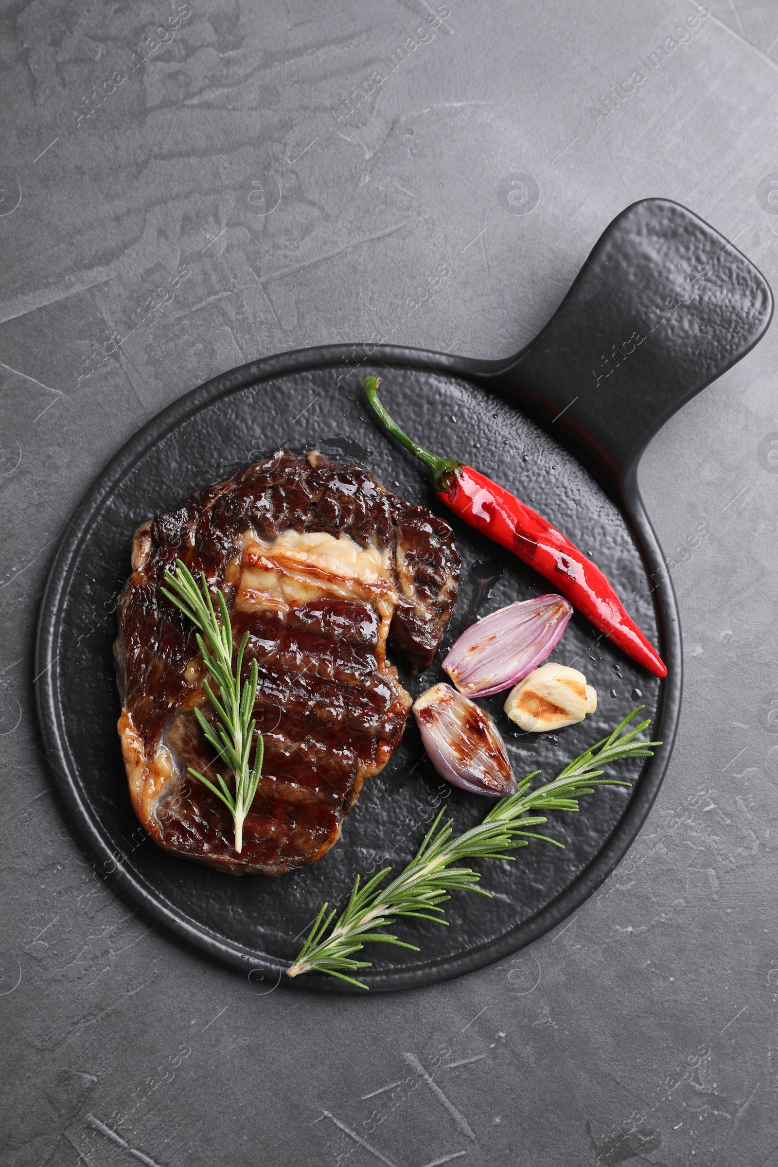 Photo of Delicious grilled beef meat, rosemary and spices on gray textured table, top view