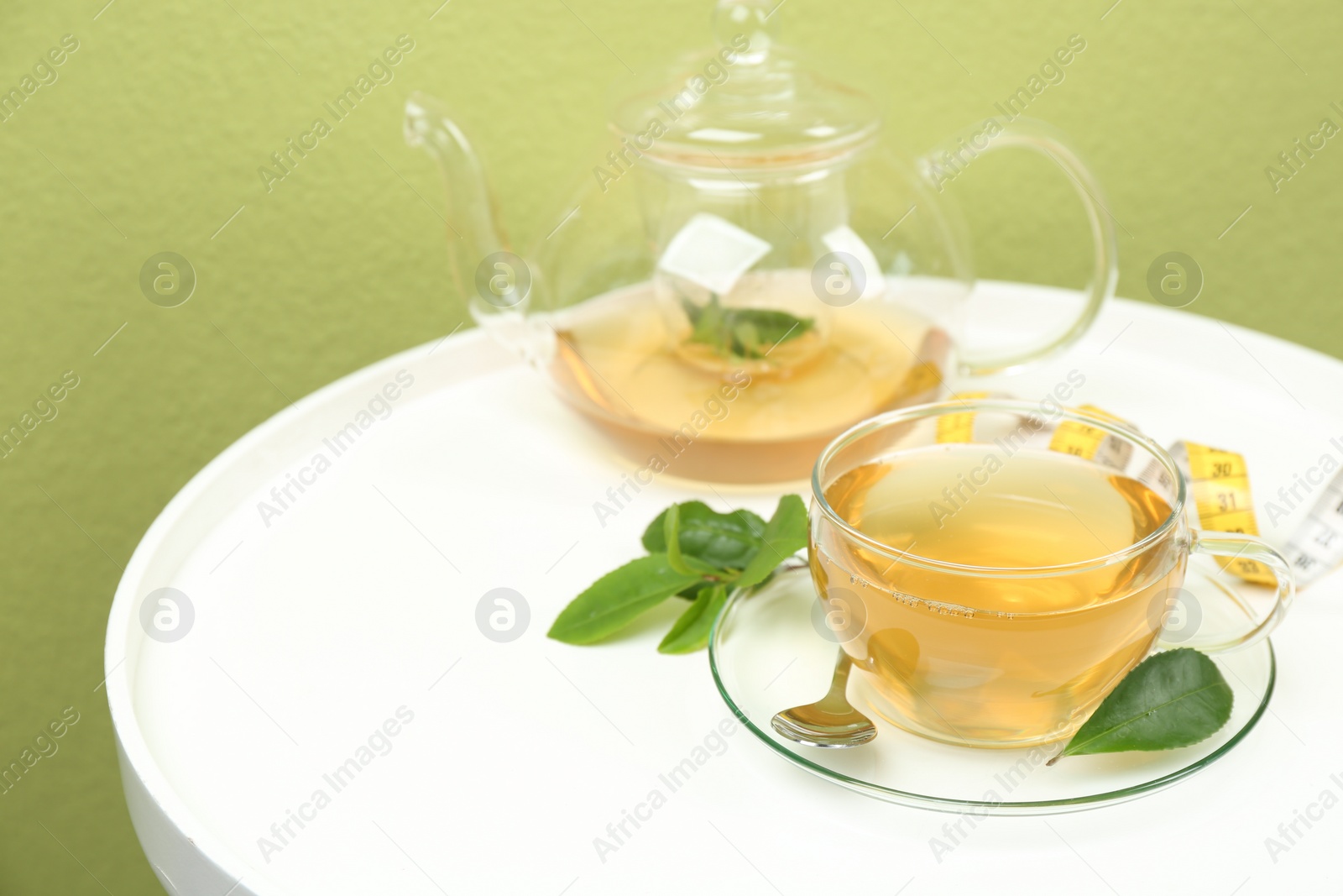 Photo of Herbal diet tea and measuring tape on white table. Space for text