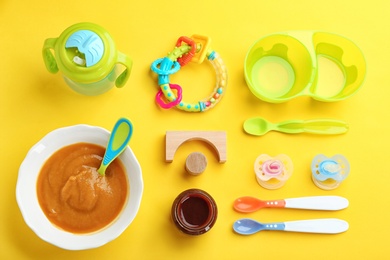 Flat lay composition with baby food and accessories on color background