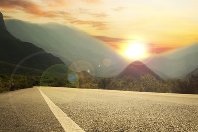 Image of Empty asphalt road, bushes and mountains at beautiful sunset