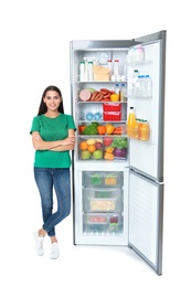 Young woman near open refrigerator on white background