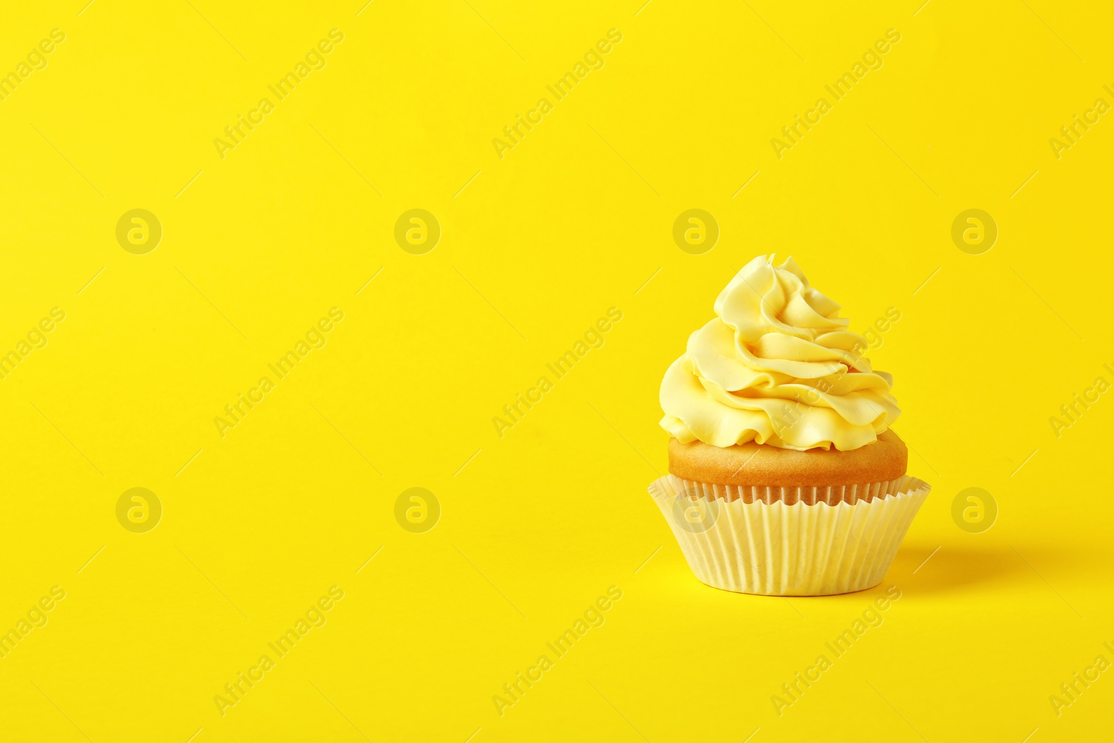 Photo of Tasty cupcake with cream on yellow background, space for text