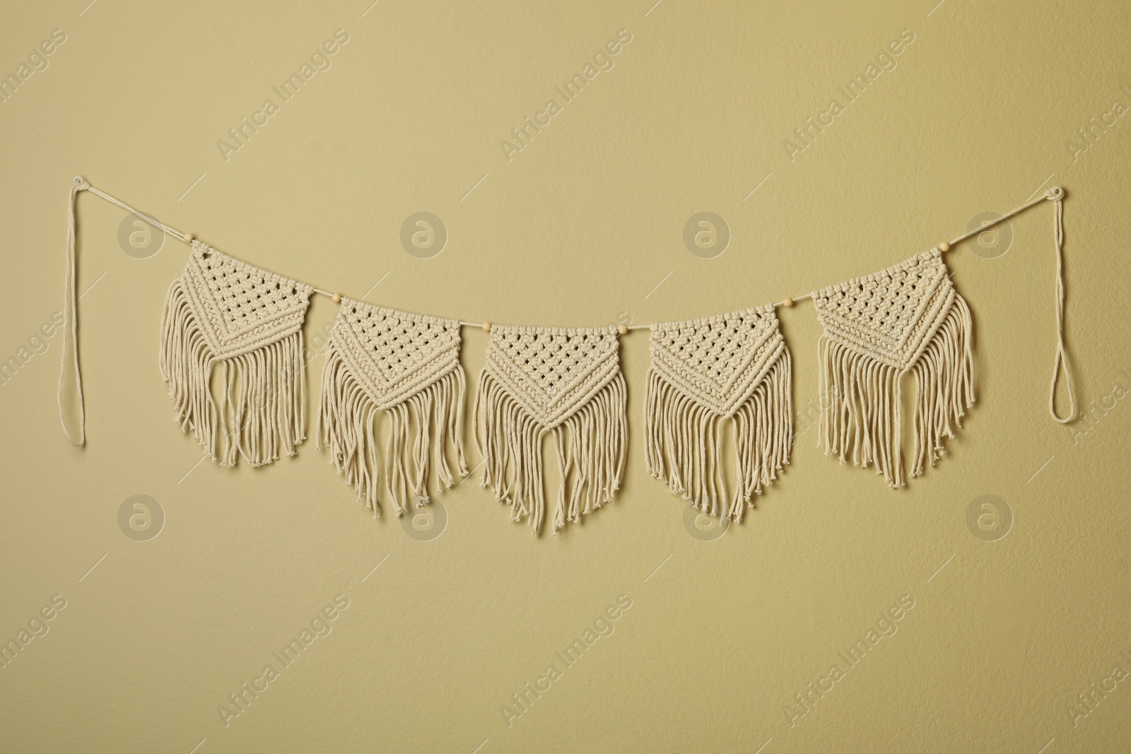 Photo of Beautiful large macrame hanging on beige wall. Decorative element