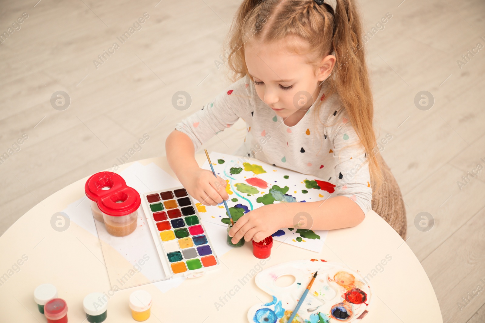 Photo of Cute little child painting at table in room