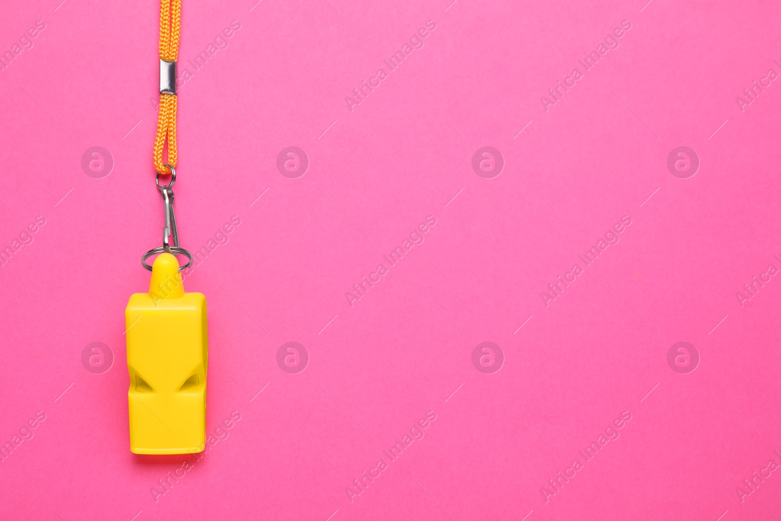 Photo of One yellow whistle with cord on pink background, top view. Space for text