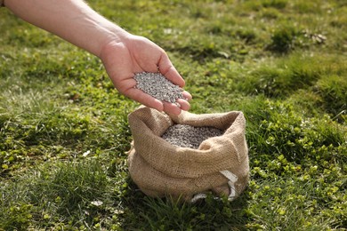 Photo of Man with fertilizer on green grass outdoors, closeup