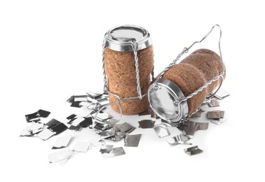 Photo of Corks of sparkling wine with muselet caps and shiny silver confetti on white background