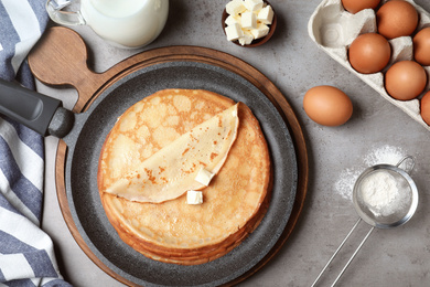 Flat lay composition with thin pancake on grey table