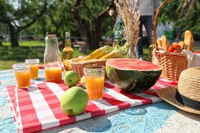Photo of Different products for summer picnic served on checkered blanket outdoors