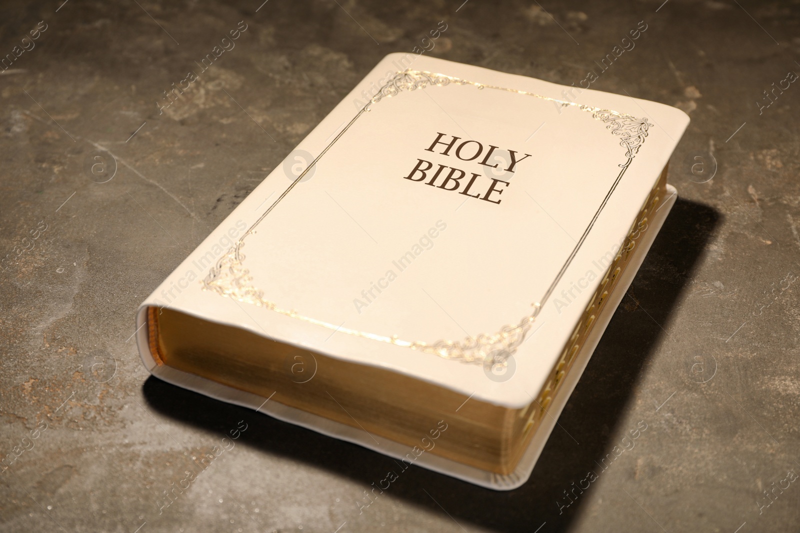 Photo of Old hardcover Bible on grey table. Religious book