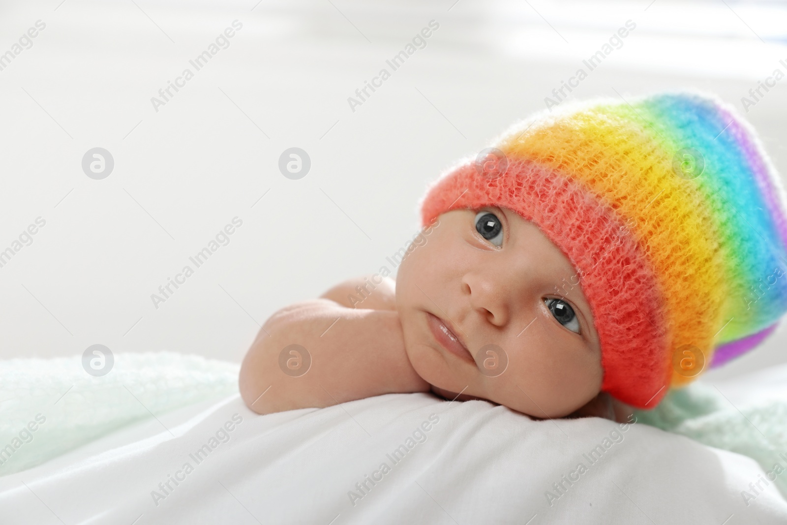 Image of National rainbow baby day. Cute child in hat with colorful pattern on blanket