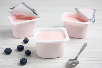 Plastic cups with tasty yogurts and blueberries on white wooden table