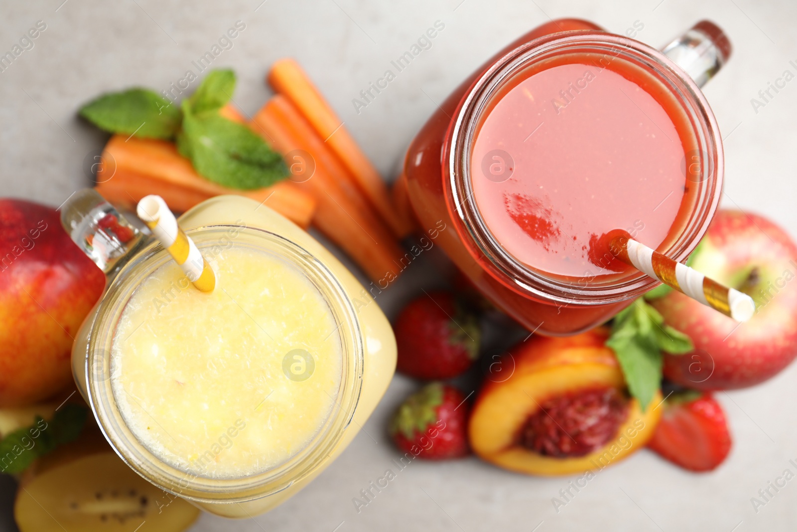 Photo of Delicious juices and fresh ingredients on grey table, flat lay