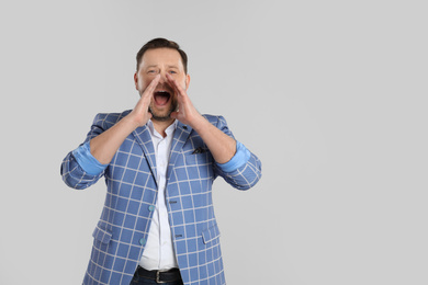 Portrait of screaming mature man on light grey background