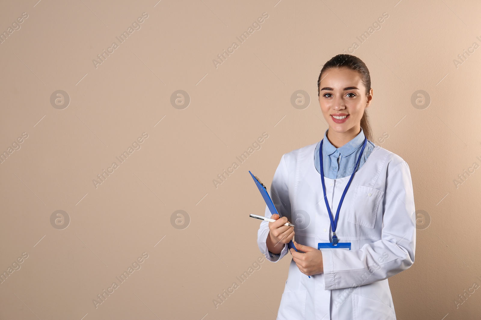 Photo of Young medical student with clipboard on color background. Space for text