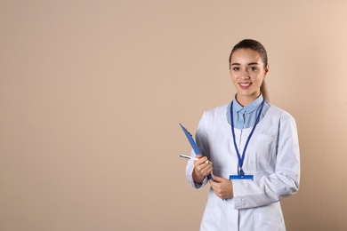 Photo of Young medical student with clipboard on color background. Space for text