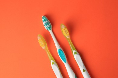Photo of New toothbrushes on orange background, flat lay