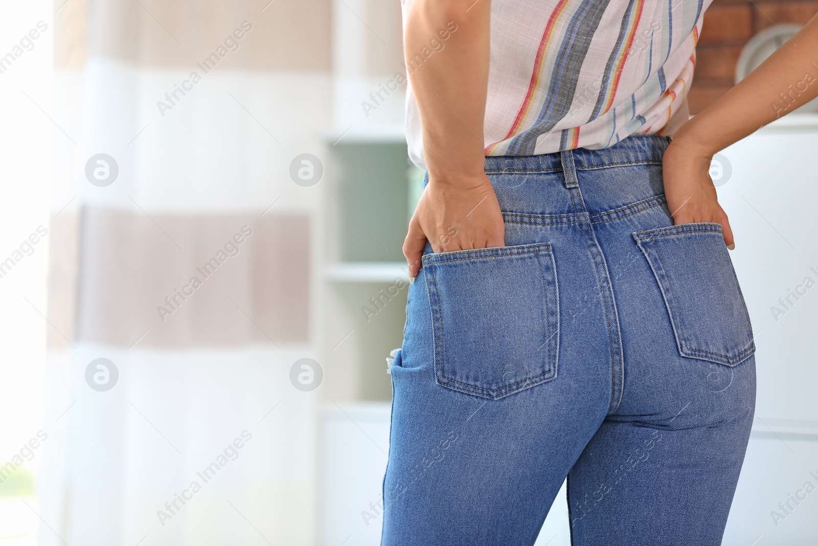 Photo of Young woman in stylish blue jeans indoors