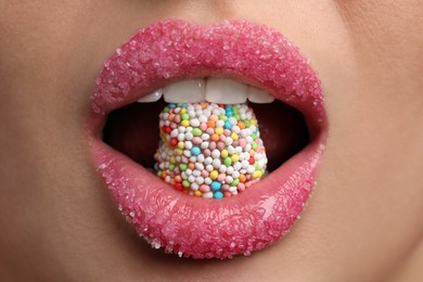 Photo of Young woman with beautiful lips covered in sugar eating candy, closeup