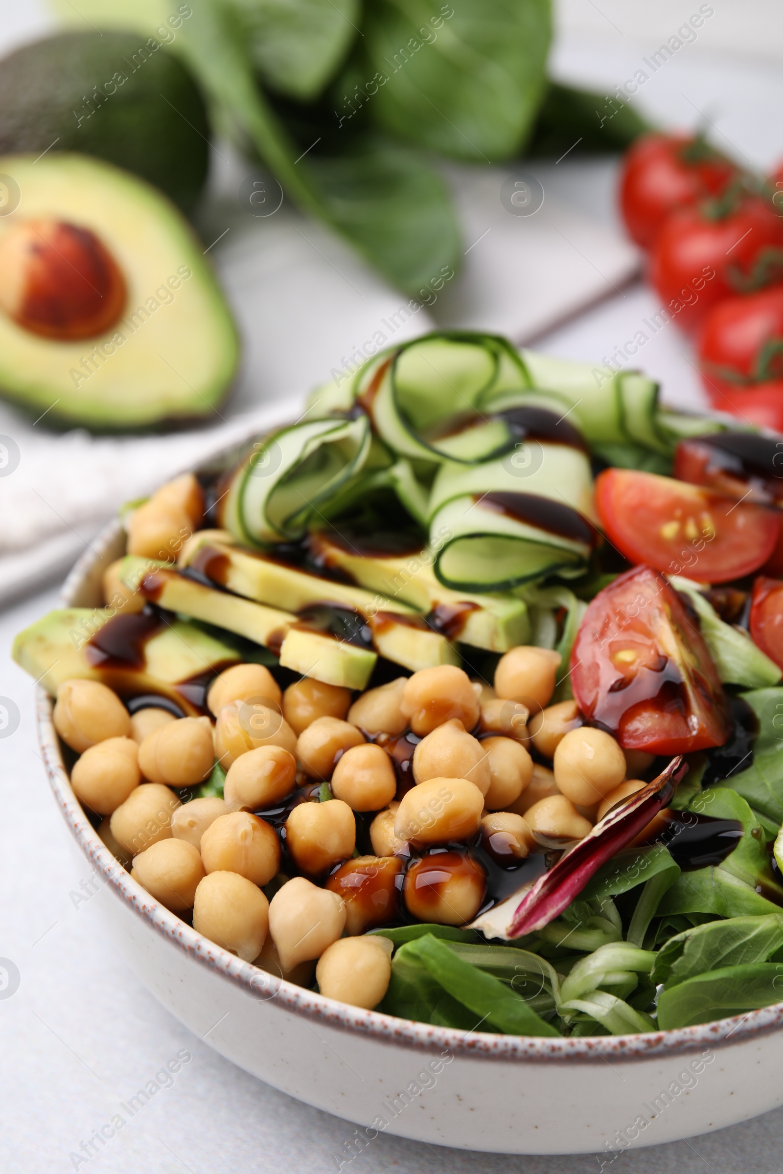 Photo of Delicious salad with chickpeas, vegetables and balsamic vinegar on white table, closeup