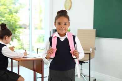 Photo of African-American girl wearing school uniform in classroom