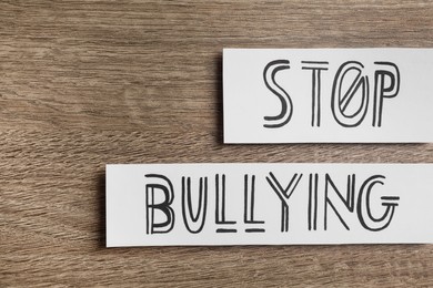 Photo of Paper cards with text Stop Bullying on wooden table, flat lay