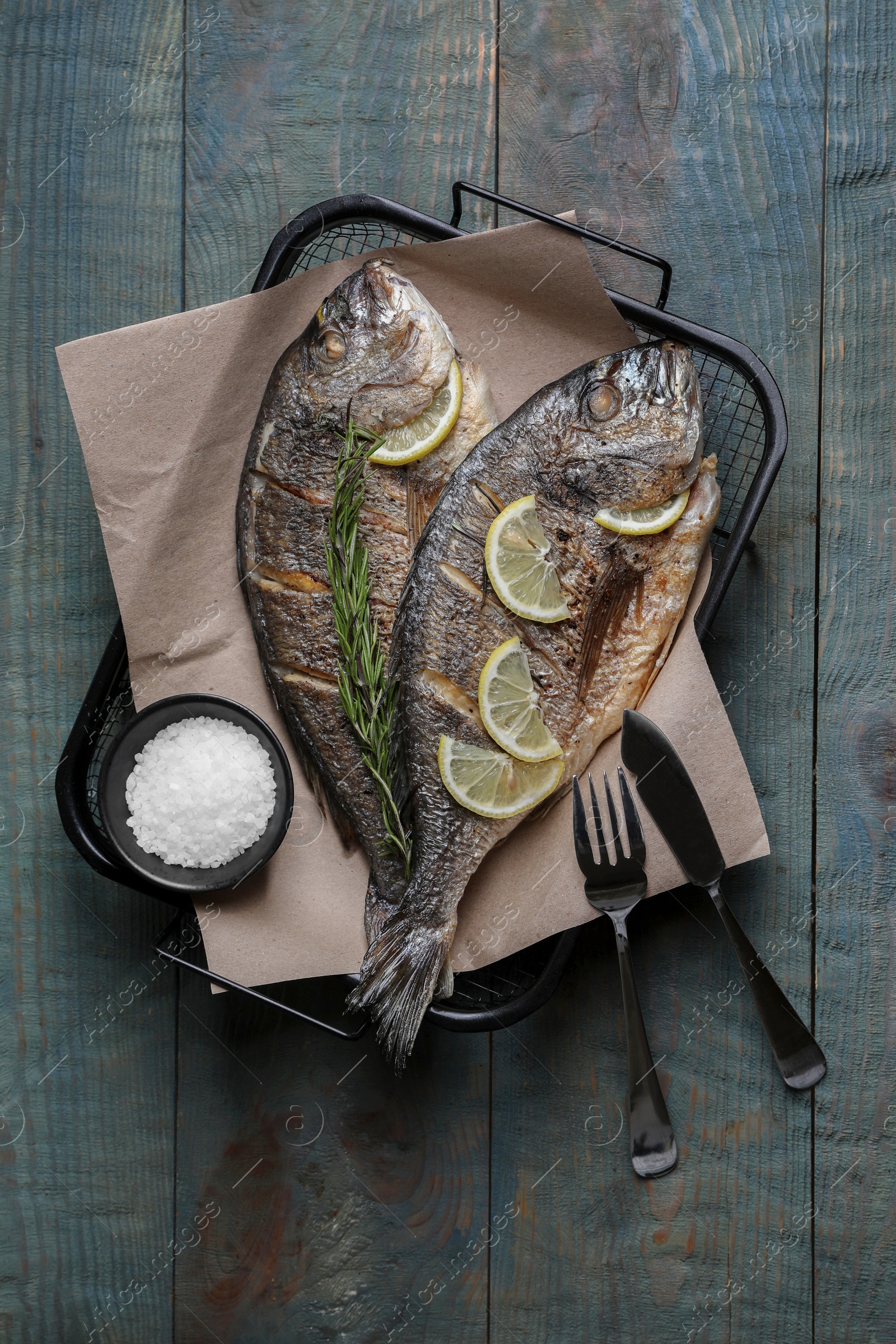 Photo of Delicious baked fish served on wooden rustic table, top view. Seafood