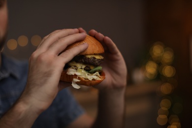 Photo of Young man eating tasty burger in cafe