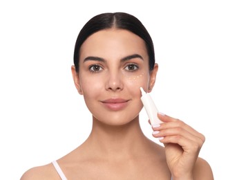 Photo of Beautiful young woman applying gel on skin under eye against white background