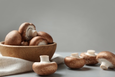 Photo of Fresh champignon mushrooms and wooden bowl on table, space for text