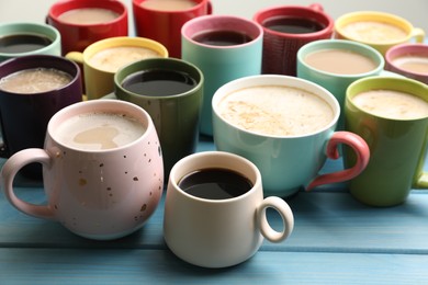 Photo of Many cups of different coffee drinks on light blue wooden table