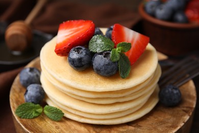 Photo of Delicious pancakes with strawberries, blueberries and mint on table, closeup