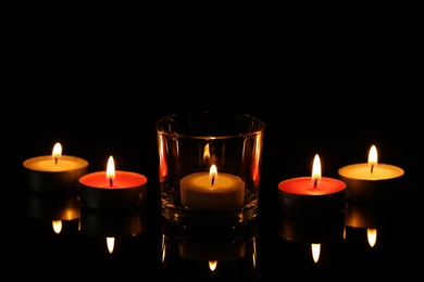 Photo of Burning small wax candles in darkness. Funeral symbol