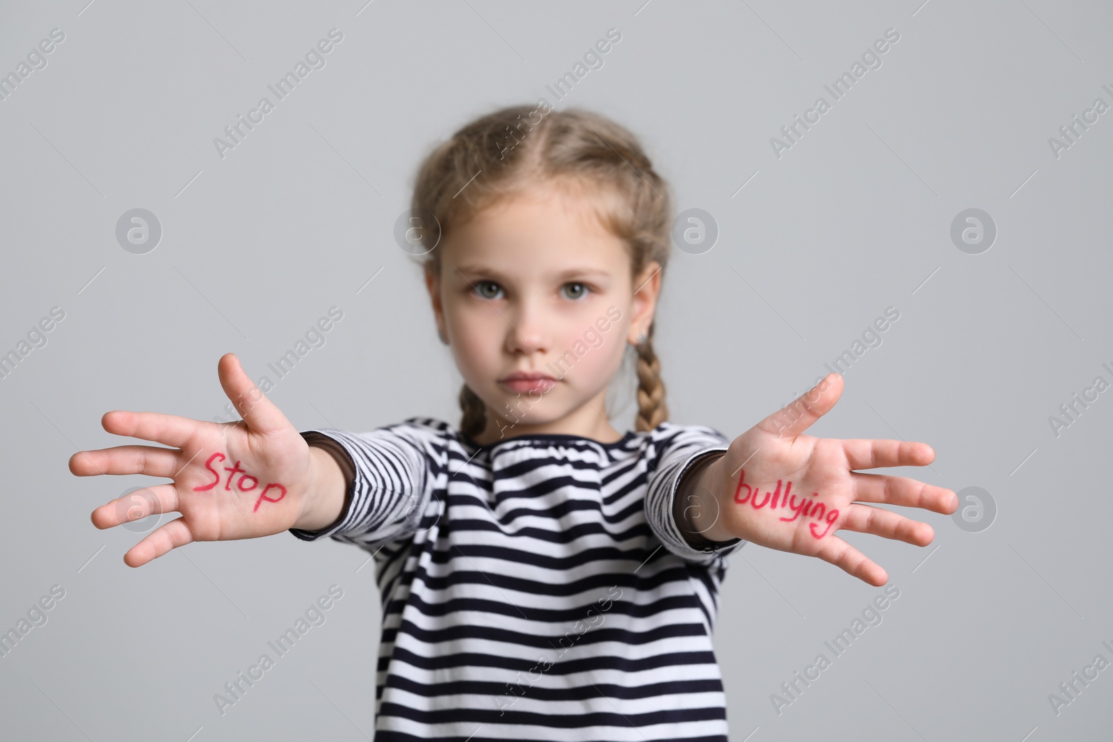 Photo of Girl showing hands with phrase Stop Bullying on light grey background, selective focus