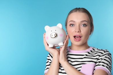 Happy young woman with piggy bank and space for text on color background. Money saving