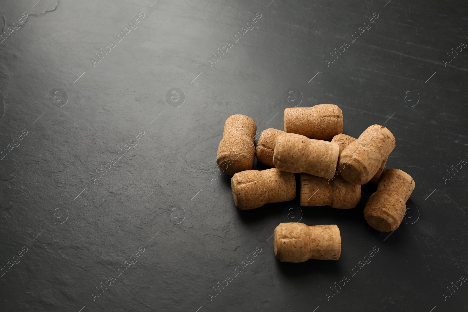 Photo of Pile of sparkling wine corks on black table. Space for text