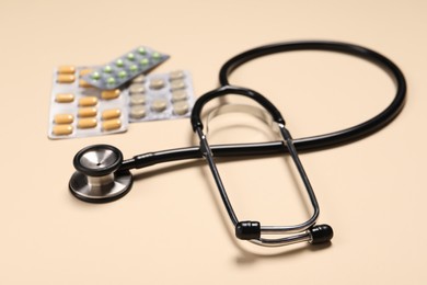 Photo of Stethoscope and pills on beige background, closeup. Medical tool