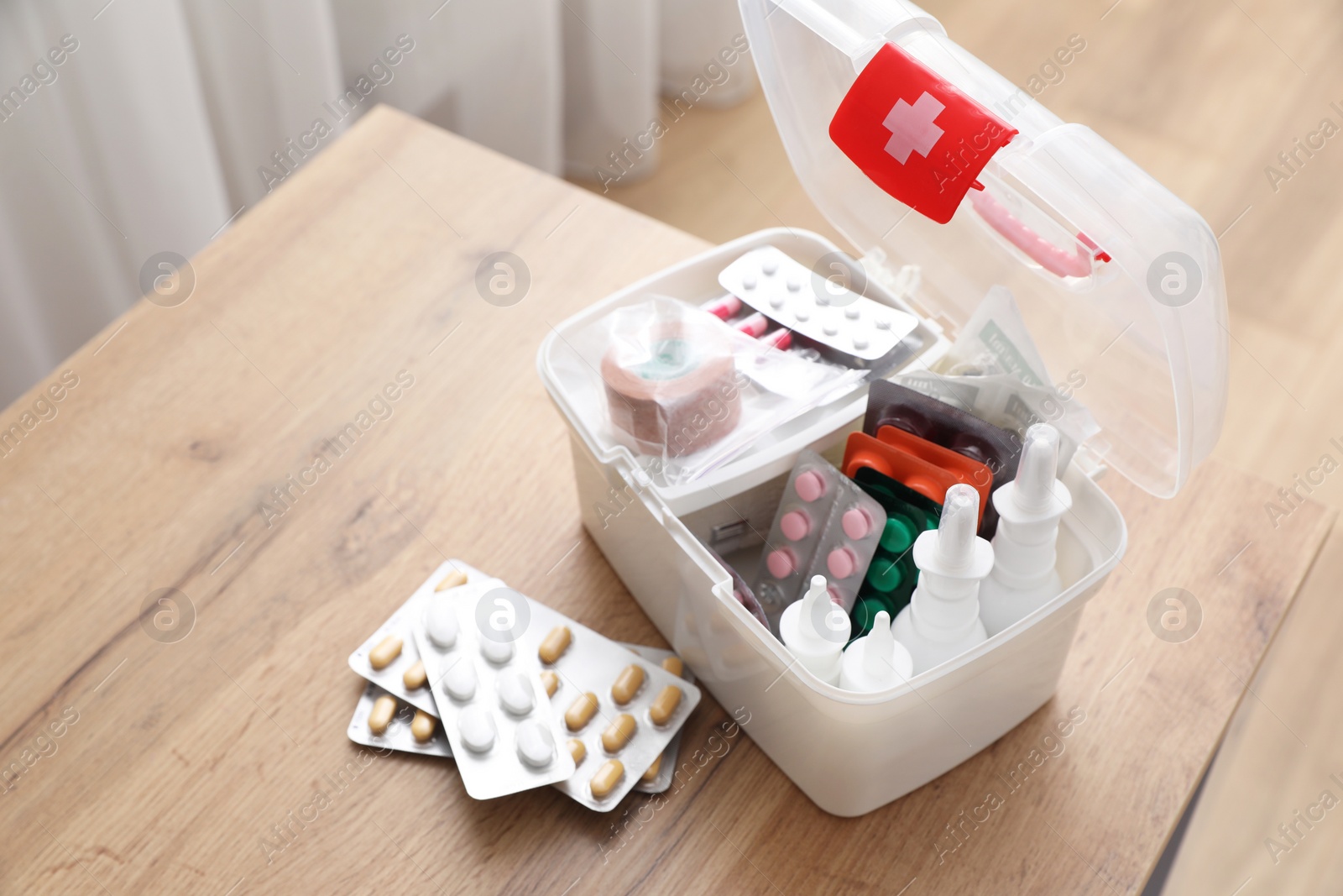 Photo of First aid kit and medicaments on wooden table indoors, space for text