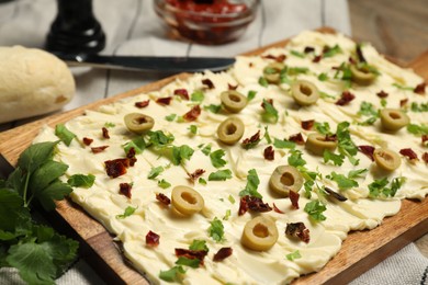 Photo of Fresh butter board with cut olives, sun-dried tomatoes and parsley on table, closeup