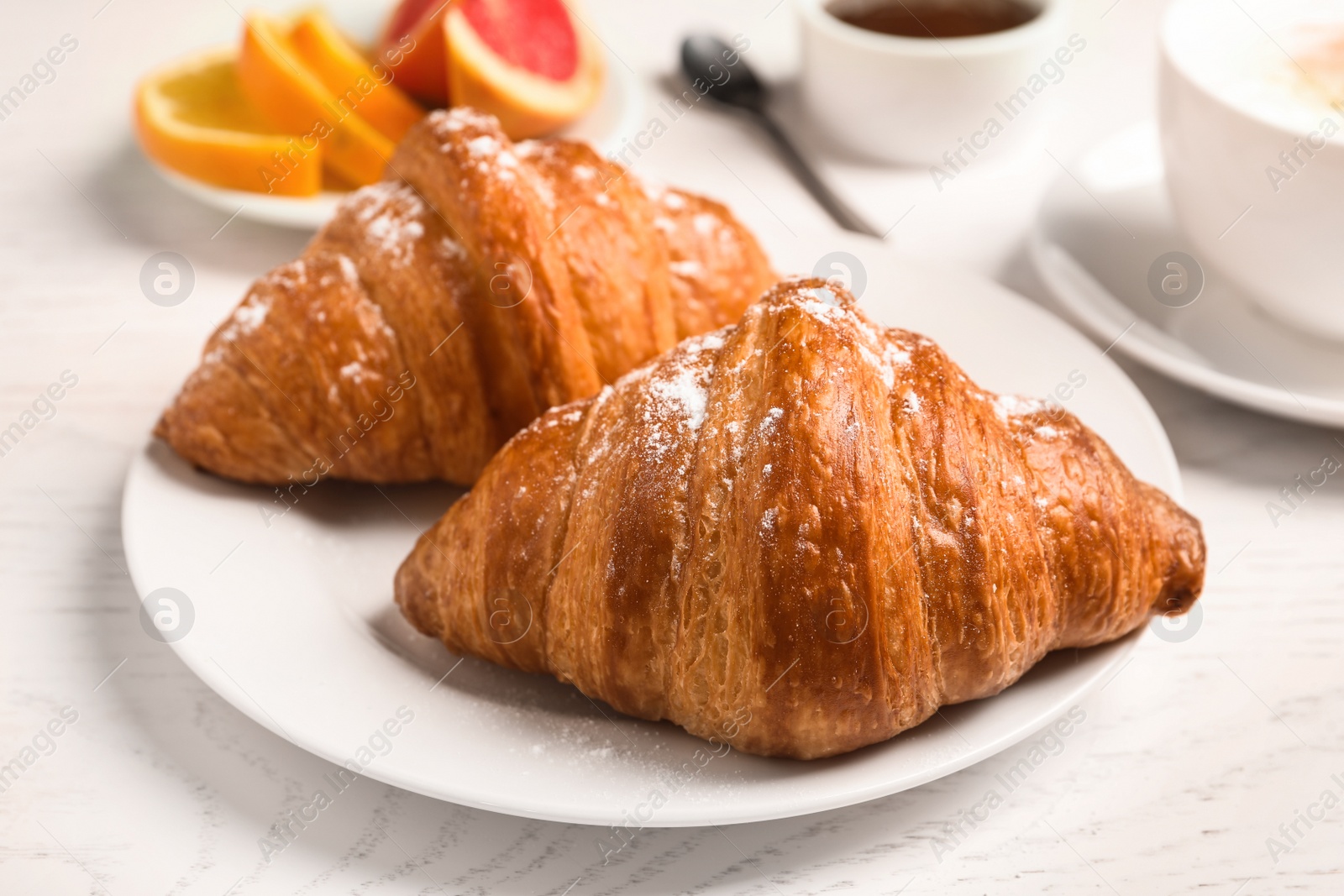 Photo of Tasty fresh croissants on white wooden table. Healthy breakfast