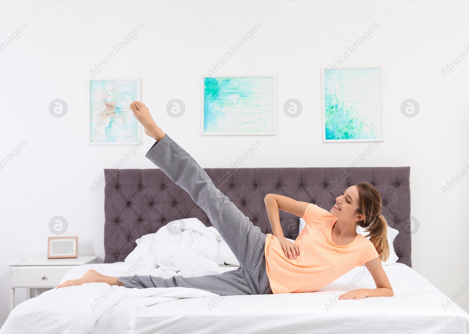 Photo of Young beautiful woman doing exercise on bed at home. Morning fitness