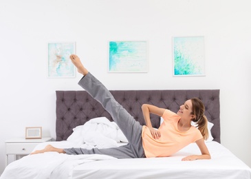 Young beautiful woman doing exercise on bed at home. Morning fitness