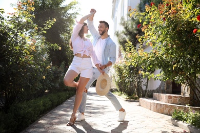 Lovely young couple dancing together in park on sunny day